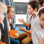 Children on a charter bus road trip, wearing headphones and using cell phones while playing games together.