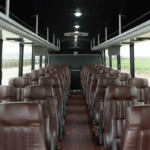 Interior of a charter bus featuring spacious seating and a large window for natural light and comfort.
